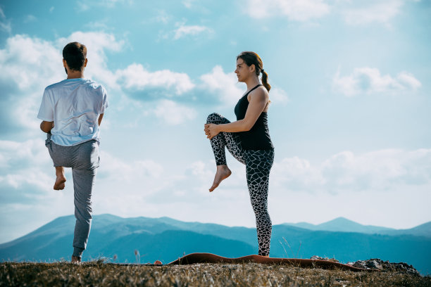 一对年轻夫妇在蓝天映衬下的山顶上打坐图片下载