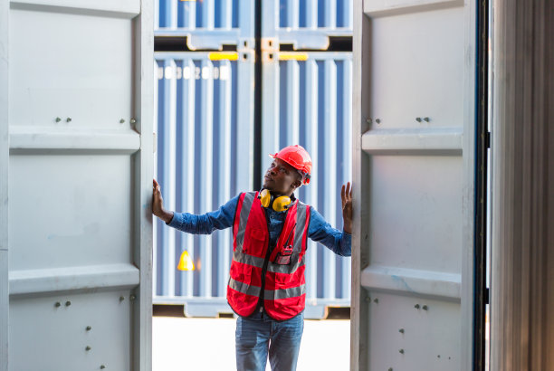 专业的领班在集装箱货场工作，检查集装箱内的货物。工人们正在打开集装箱接受检查。图片下载