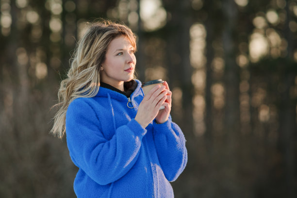 美丽的年轻女子喝着咖啡，在公园里享受美丽的冬日图片下载