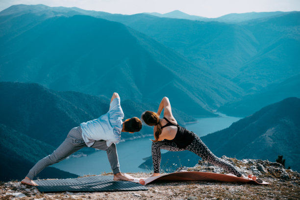 日落时分做瑜伽的年轻夫妇。健康的生活方式图片下载