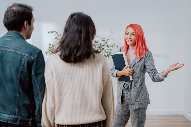 夫妇约房地产中介粉红色头发穿着优雅的业主邀请他们去市中心看新装修的公寓年轻人想租买第一套房图片下载