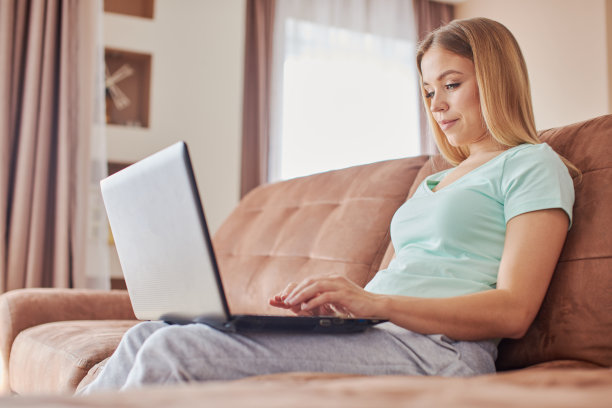 漂亮的金发女人在家用笔记本电脑工作图片下载