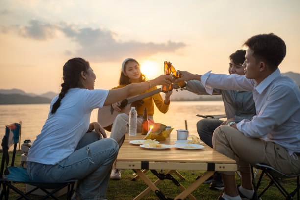 一群快乐的亚洲朋友，弹吉他，唱歌，享受露营和喝啤酒图片下载