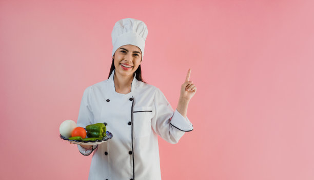 年轻的拉丁女子戴着厨师帽，在粉红色的背景下烹饪墨西哥食物图片下载