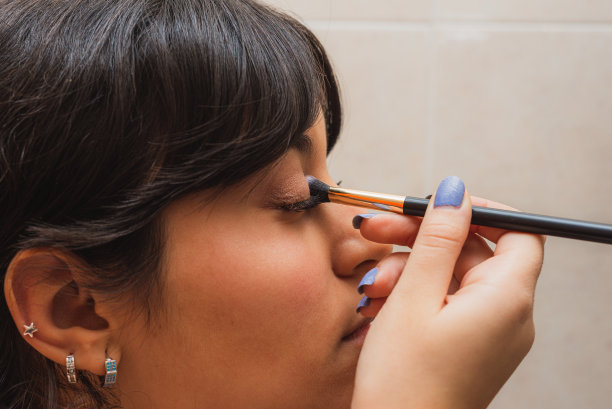 年轻女子在镜子前用刷子化妆。图片下载