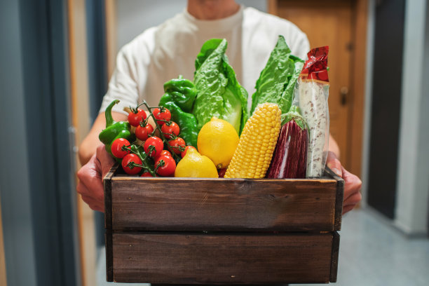 送外卖的人拿着装着食物的纸袋站在门口。快递员把装有新鲜蔬菜和水果的盒子交给顾客图片下载