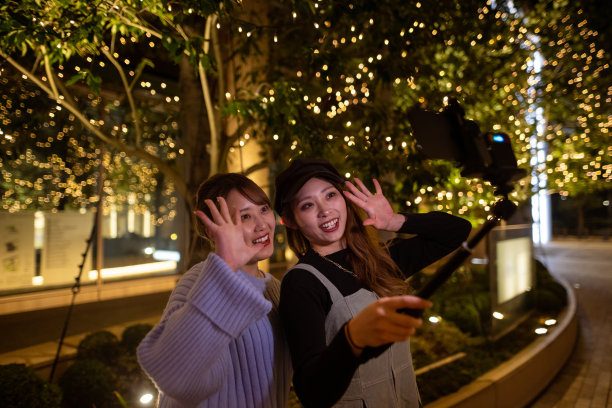 年轻的女性朋友们在圣诞灯光下在街上拍视频图片下载