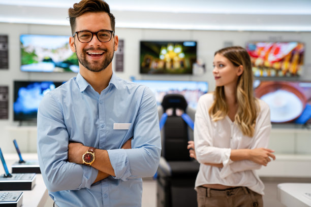 快乐的售货员帮助女士在科技商店购买新的数字智能设备。图片下载