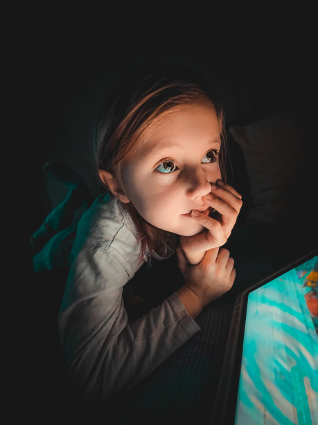 小白种人女孩晚上在黑暗的床上看着平板电脑，生活方式色调摄影在家里图片下载