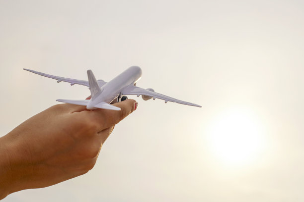 近距离的照片，女人的手拿着玩具飞机对抗阳光明媚的天空和云彩。旅行的概念，交通工具，梦想假期图片下载