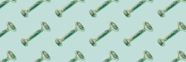 条幅图案，由翡翠挂沙颜面滚子在粉彩绿色的背景。面部按摩包，由天然石材制成的提升按摩疗法，个人护肤抗衰老工具图片下载