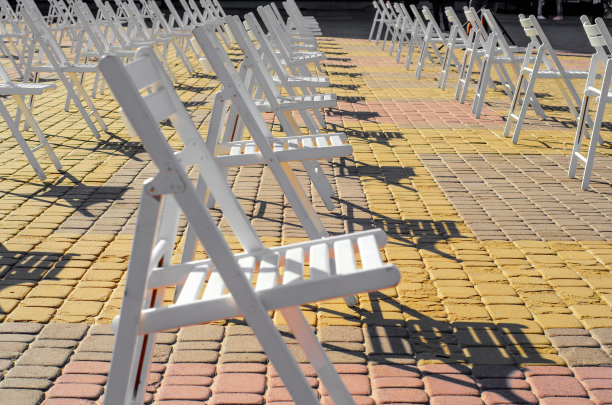白色的折叠椅放置在广场上的人行道上。隔离限制，群众性活动，街头音乐会图片下载