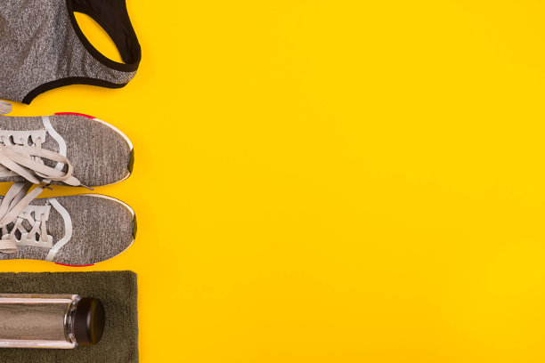 黄色背景的运动员套装，女性服装，哑铃和水瓶图片下载