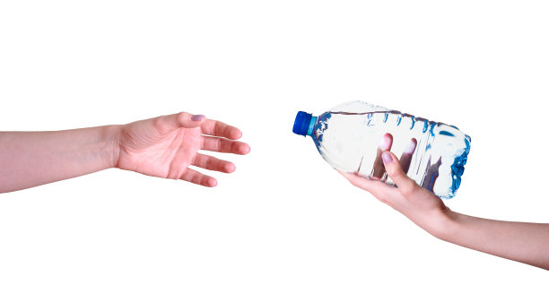 一个女人拿着一瓶水的手传到另一只手上，背景是白色的。图片下载