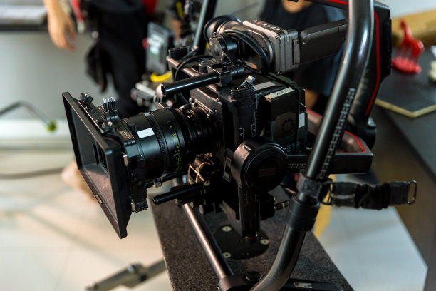 电影拍摄或摄制及摄制组配备摄影器材。摄像机操作员与设备一起工作。摄影导演，手里拿着相机在片场图片下载