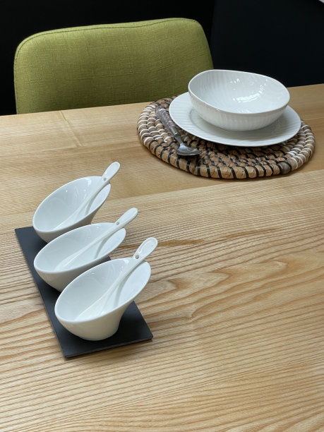 木制厨房餐桌的特写图像，由橡木木材薄片，早餐/午餐/晚餐与白色盘子和盘子，圆形柳条餐具垫，现代汤匙与塑料手柄，软橄榄绿色坐垫椅子图片下载