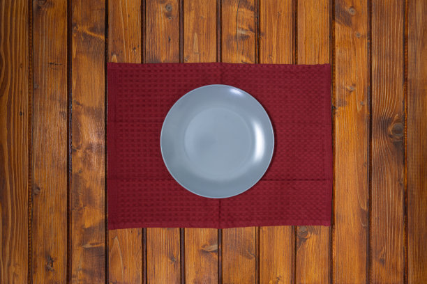 在木桌上红色餐巾或抹布上的空灰色盘子的俯视图图片下载