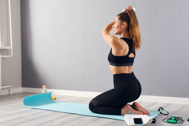 健身女孩在家锻炼后休息。健身女性在锻炼后坐在地板上放松。健身、放松、待在家里的理念。图片下载