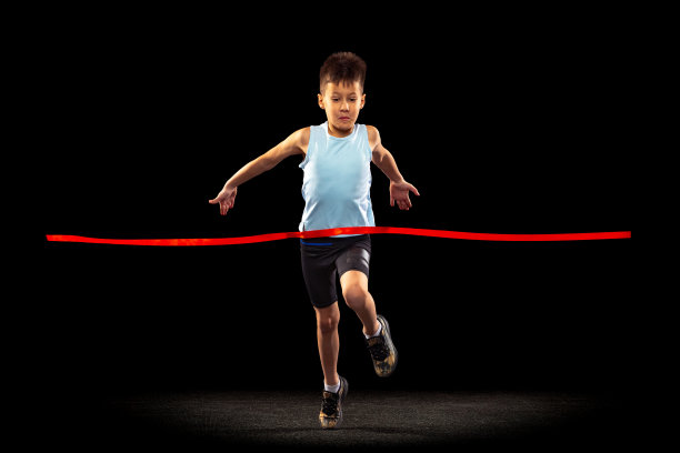 男孩的全长肖像，孩子跨越红色丝带孤立在黑色背景。赢家图片下载