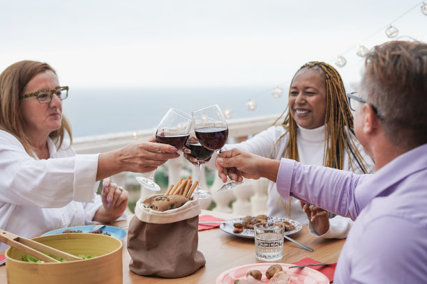 多种族的老年朋友在露台上用红酒庆祝晚餐图片下载