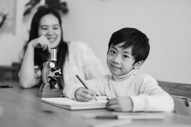 亚洲孩子在家里和保姆一起画画，对着镜头微笑图片下载