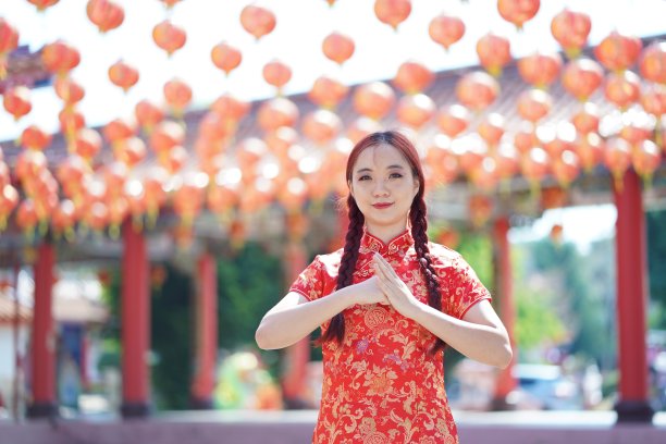 春节快乐。亚洲妇女穿着传统的旗袍，以旗袍的手势表示祝贺图片下载