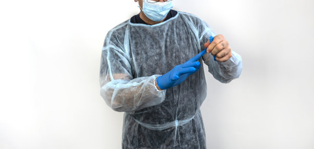 照片中一名医生戴着帽子，手套，拿着注射器图片下载