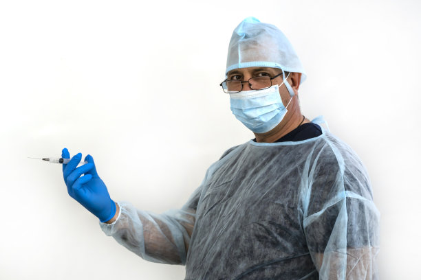 照片中一名医生戴着帽子，手套，拿着注射器图片下载
