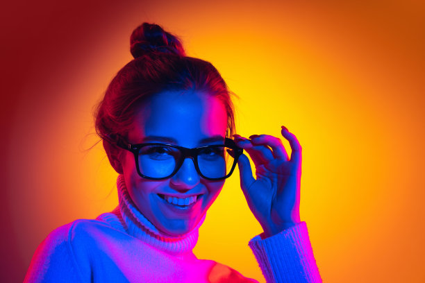 年轻美丽的女孩在霓虹灯，滤镜的橙色背景孤立的半身肖像。概念情感，表情，青春，抱负，销售图片下载