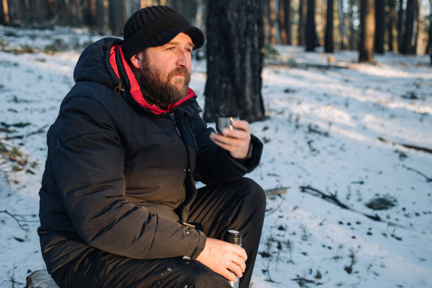 冬天的森林里，一个满脸胡须的男人坐在那里喝茶图片下载