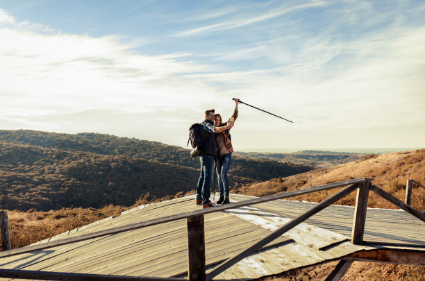 一对背着背包的情侣在爬山时自拍。图片下载