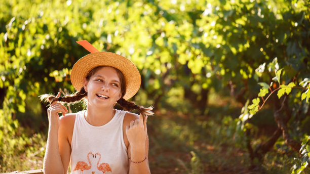 年轻快乐女孩的肖像与草帽绿色模糊的vyneyard和背景。青少年享受夏日生活图片下载