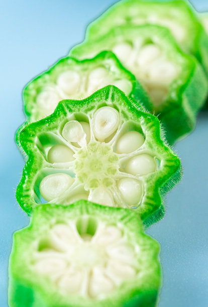 新鲜秋葵蔬菜切片孤立在蓝色背景股票照片。图片下载