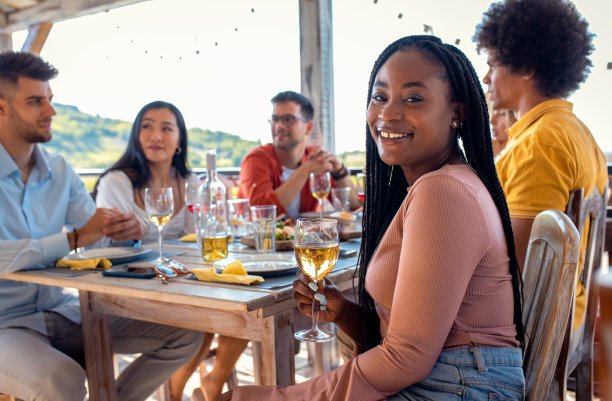 年轻女子与一群朋友在聚会上吃饭喝酒的照片。图片下载
