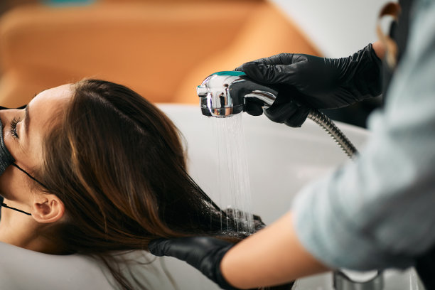 美发师洗头发的一个女人在沙龙的特写。图片下载