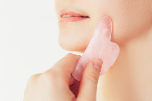 女孩用石头按摩器按摩她的颧骨图片下载