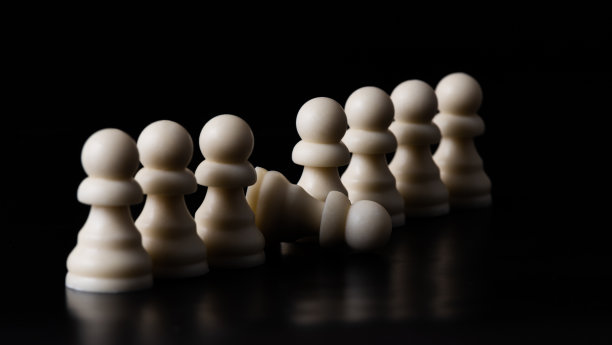 棋子排成一排，其中一个躺在黑色的背景上图片下载