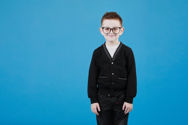 戴眼镜的可爱小男孩在灰色的背景上微笑着，玩得很开心。快乐的童年。本空间图片下载