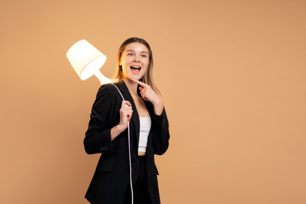 创造力和创新精神是成功的关键。以灯光照明的新理念和创新理念。美丽微笑的白种人女人手里拿着灯，微笑孤立。图片下载