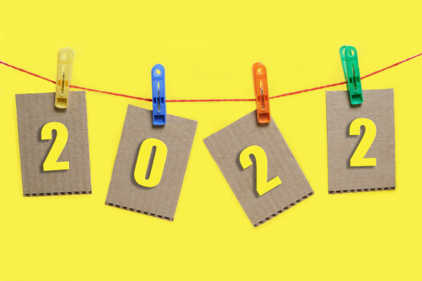 2022年的数字被挂在纸板上，挂在黄色背景的晒衣夹上。图片下载