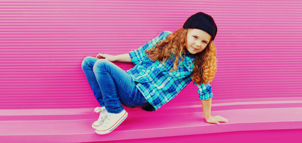 时尚的青春期前卷发女孩跳舞在粉红色的背景棒球帽图片下载