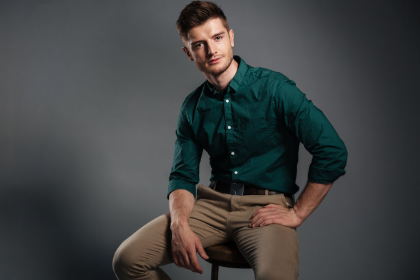 专注的年轻人孤立地坐在灰色的背景上图片下载