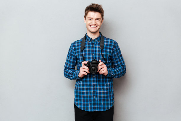 快乐的男人拿着相机摆出孤立的姿势图片下载
