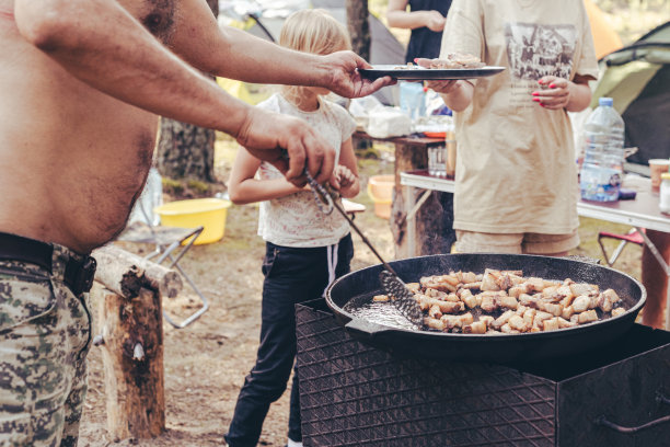 一个男人在营火上做饭。图片下载
