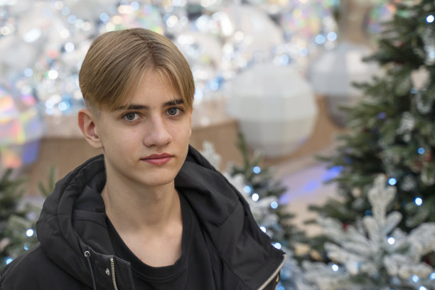 一个少年的肖像，在圣诞树的背景下望向一边。图片下载