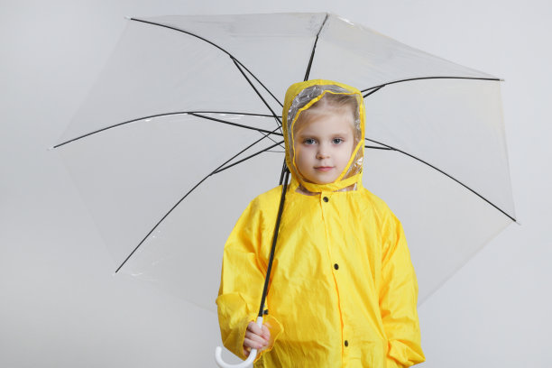 可爱的小女孩穿着黄色雨衣，拿着雨伞图片下载