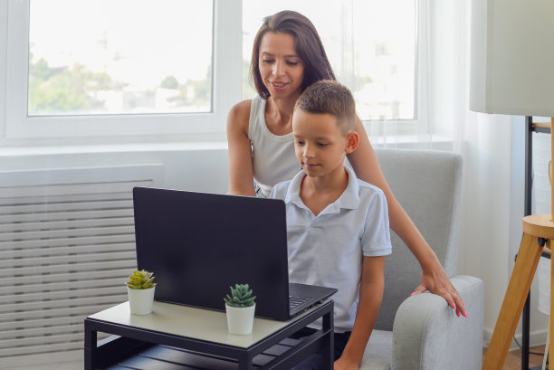男孩与妈妈使用笔记本电脑和在线学习视频电话老师在家里。在家教育,远程教育图片下载