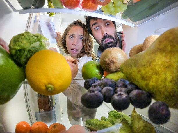 年轻的男女害怕地看着冰箱里的水果和蔬菜图片下载