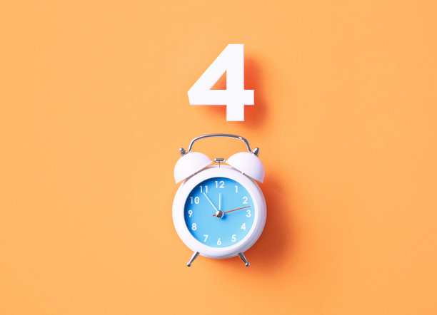 坐在橙色背景的白色闹钟上面图片下载