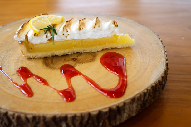 一片柠檬挞放在木盘上，用草莓酱装饰。图片下载